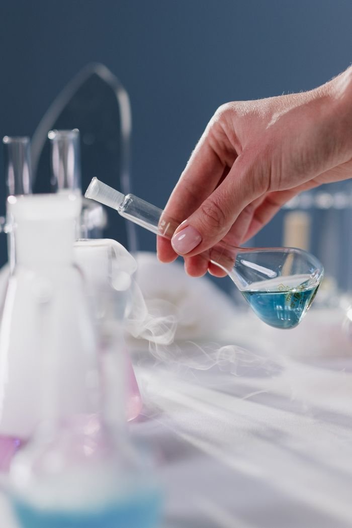 Close-up of a hand holding a flask in a laboratory setting with smoke effect.