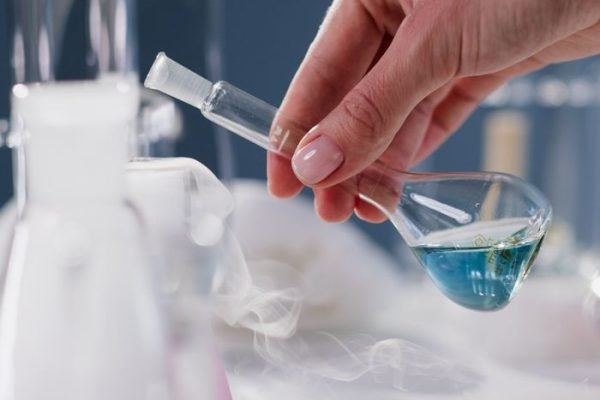 Close-up of a hand holding a flask in a laboratory setting with smoke effect.