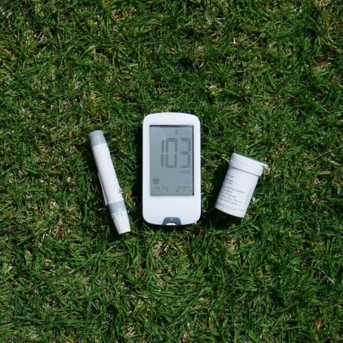 Diabetes management tools including glucose meter and test strips on grass, highlighting outdoor use.