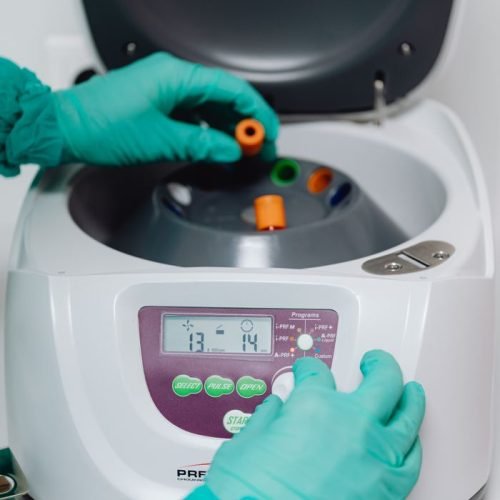 Close-up of a laboratory technician operating a centrifuge machine for sample processing.