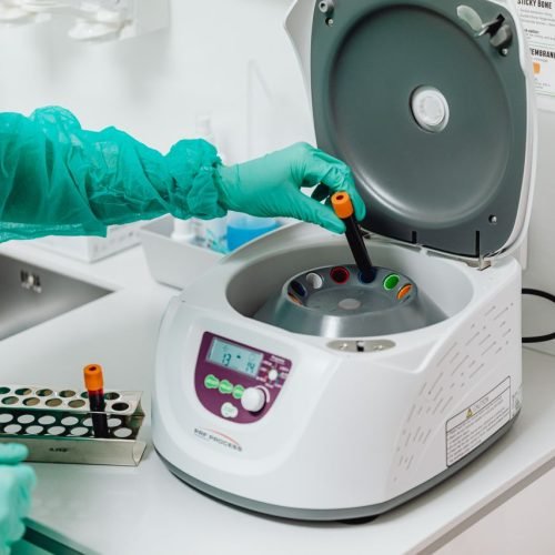 A healthcare professional operates a centrifuge machine in a laboratory, ensuring sterile medical procedures.