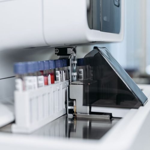 Close-up of an automated laboratory machine handling test tubes for research.