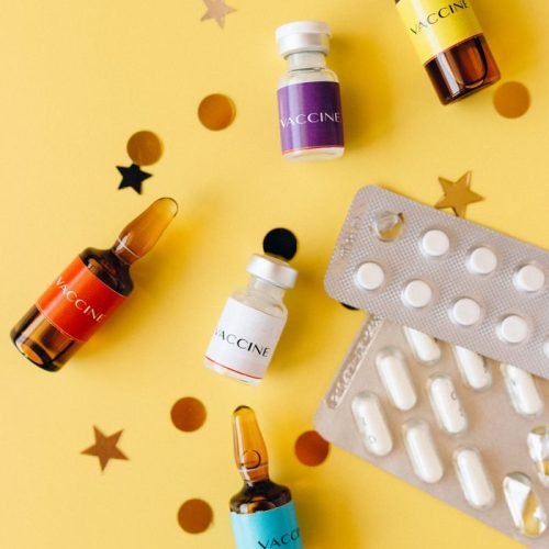 Vibrant still life featuring vaccine vials and pills on a yellow background, ideal for healthcare themes.